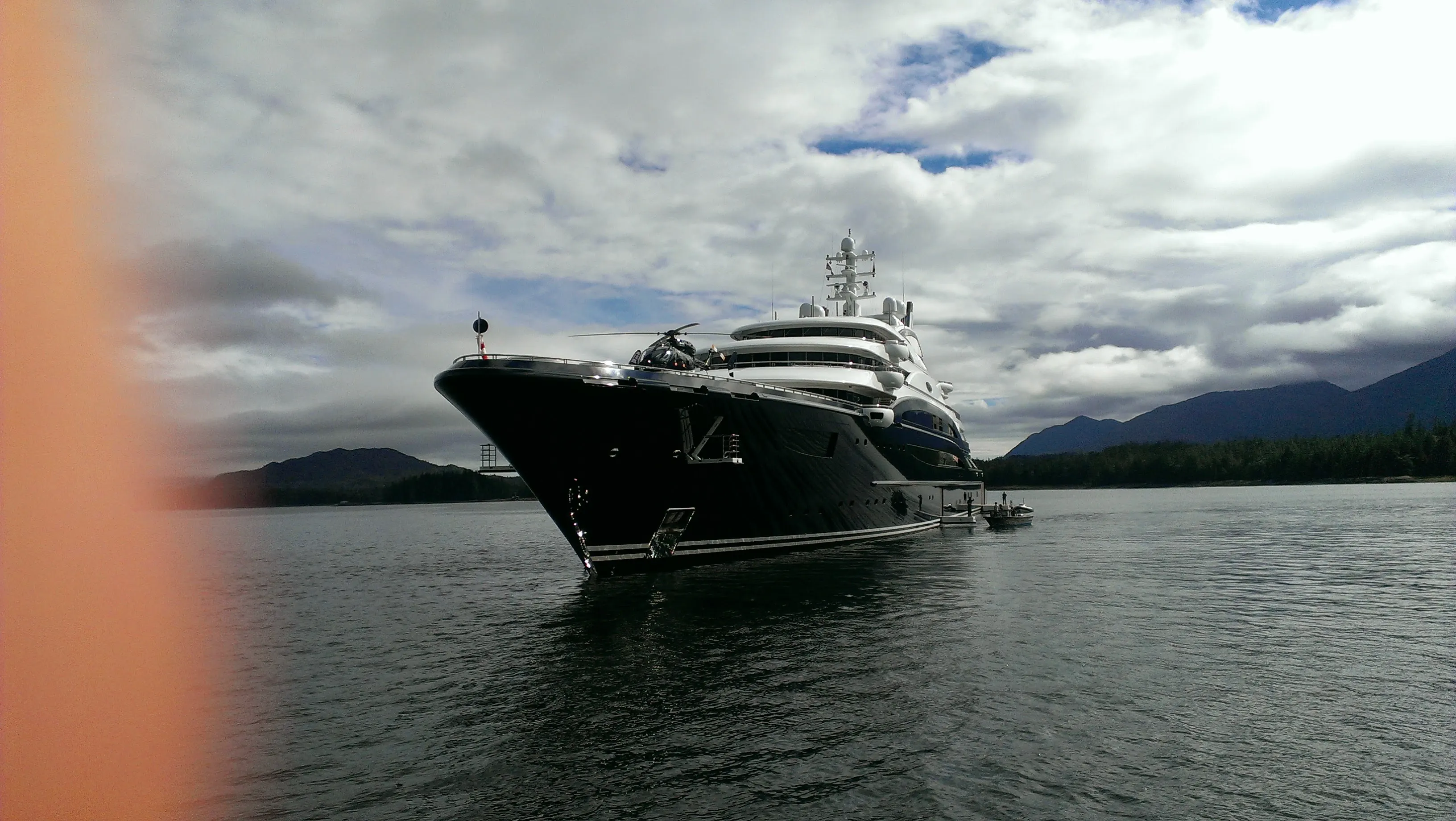 Large motor yacht at anchor below cloud-covered mountains
